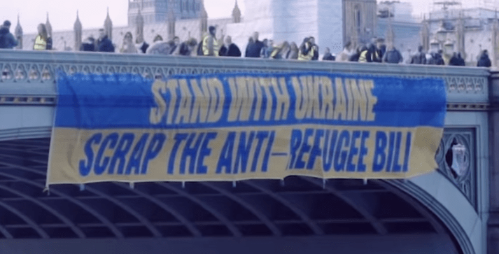 Banner drop reads "Stand with Ukraine Scrap the anti-refugee bill"